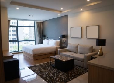 Cozy studio apartment design with bedroom and living space. Hotel room panoramic window, double bed, sofa and coffee table. Urban apartment concept