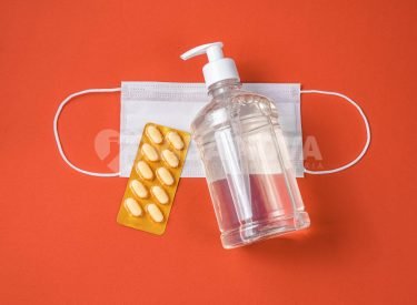 Alcohol gel container, surgical mask, medicine on the red background