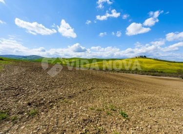 Italian landscape with meadows early in the spring. Agriculture in Italy, plowed fields, pastures and farmhouse on the hill.